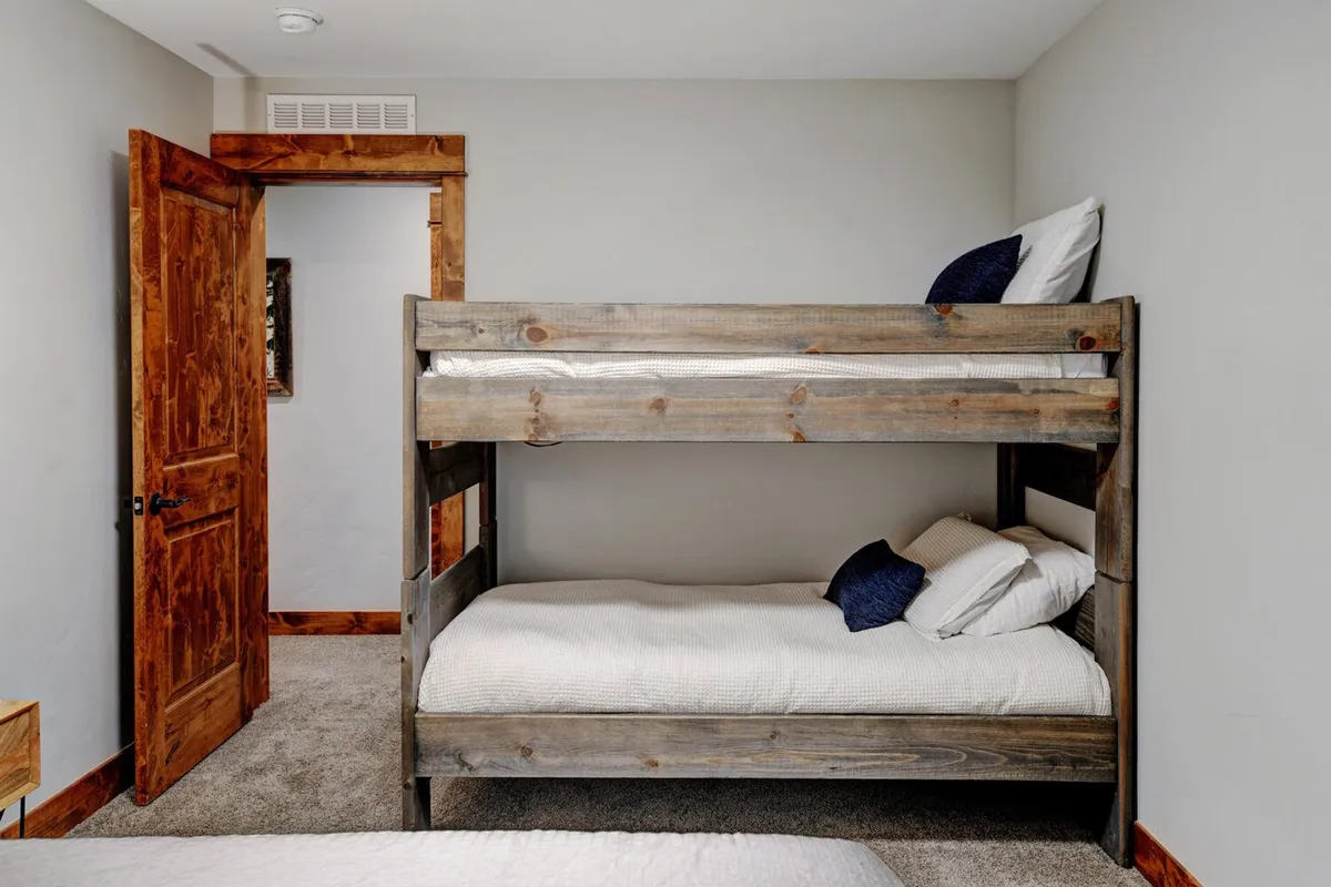 A cozy bunk room with a sturdy wooden bunk bed and textured walls, inviting relaxation, storytelling, or playful moments for children or the young at heart.