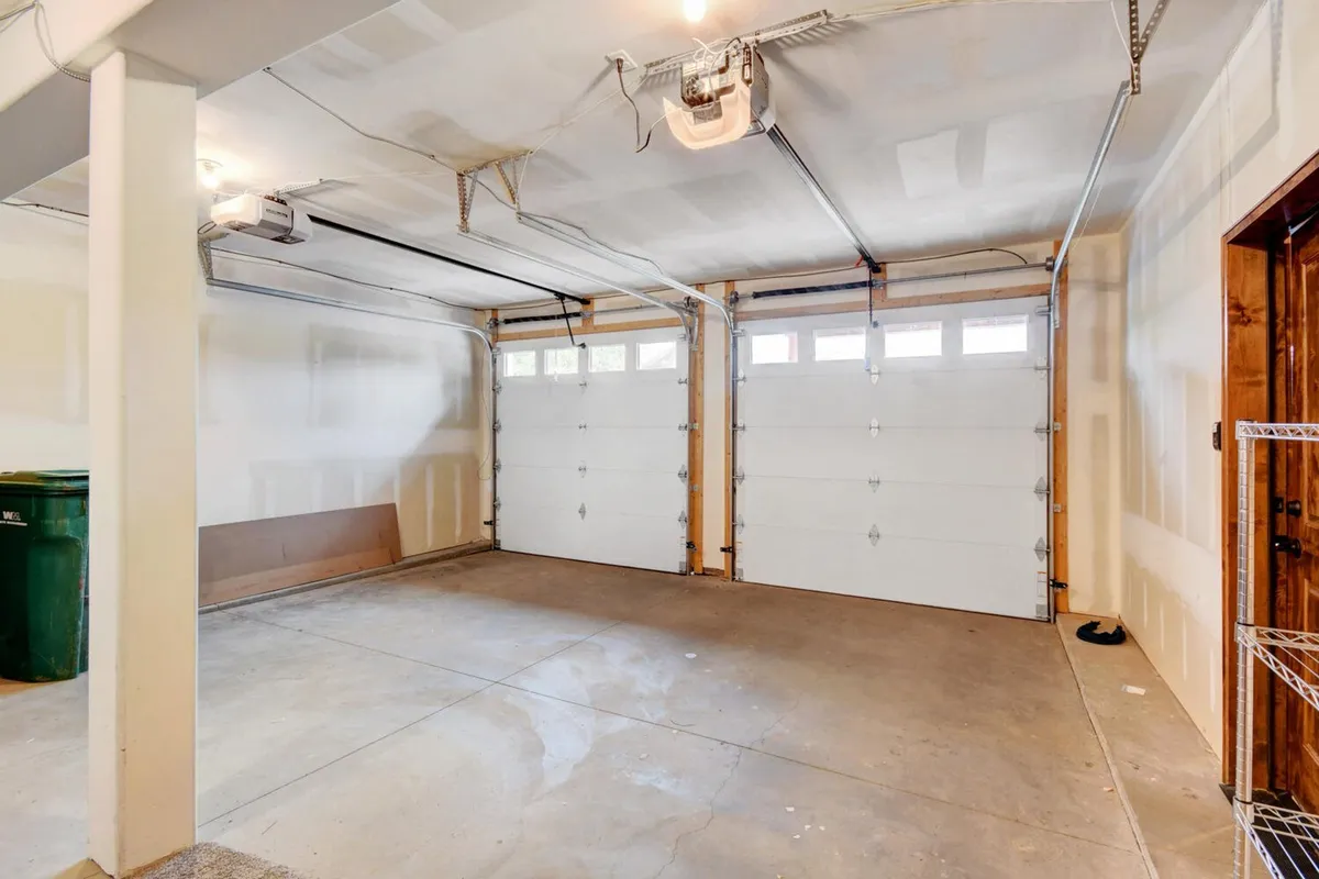 A spacious, organized garage featuring open space, storage shelving, and large garage doors. The scene is uncluttered and clearly designed for both vehicle parking and storage of outdoor gear or adventure equipment.